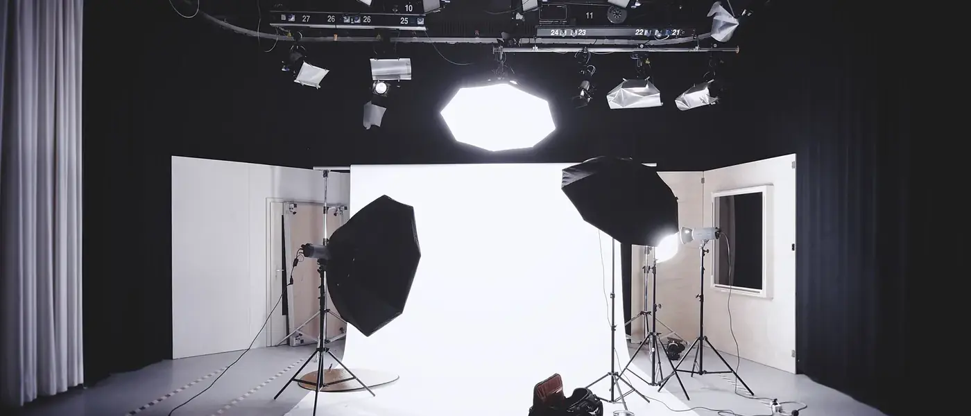 A film studio with a white backdrop, two softbox lights on stands and an overhead lighting rig
