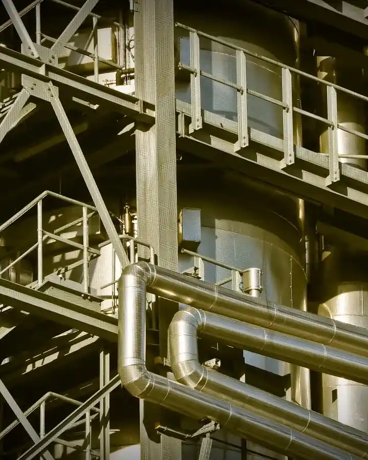 Gantry steps and insulated pipe runs climbing through a plant building